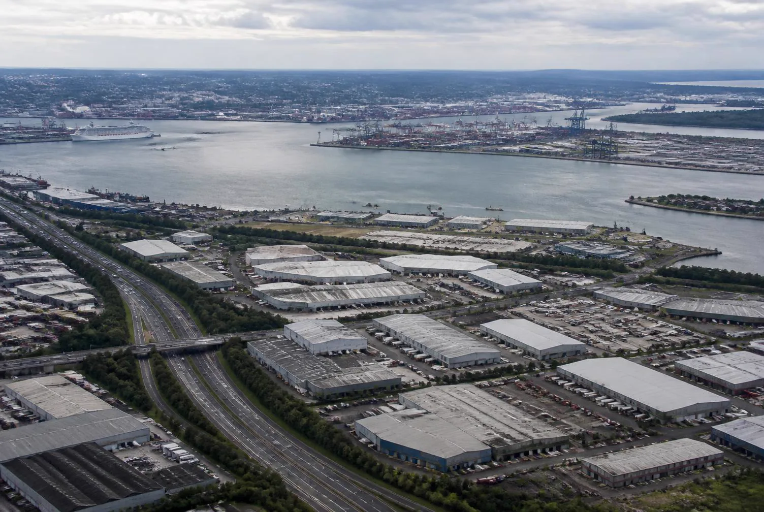 Aerial view of a waterway, dockside cranes, warehouses and roads